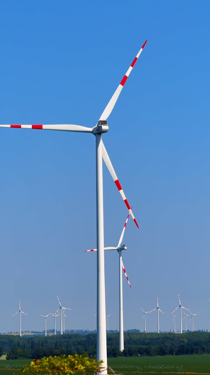 Turbines create clean energy. Wind turbines stand tall against a clear blue sky, harnessing wind energy in a rural landscape surrounded by greenery