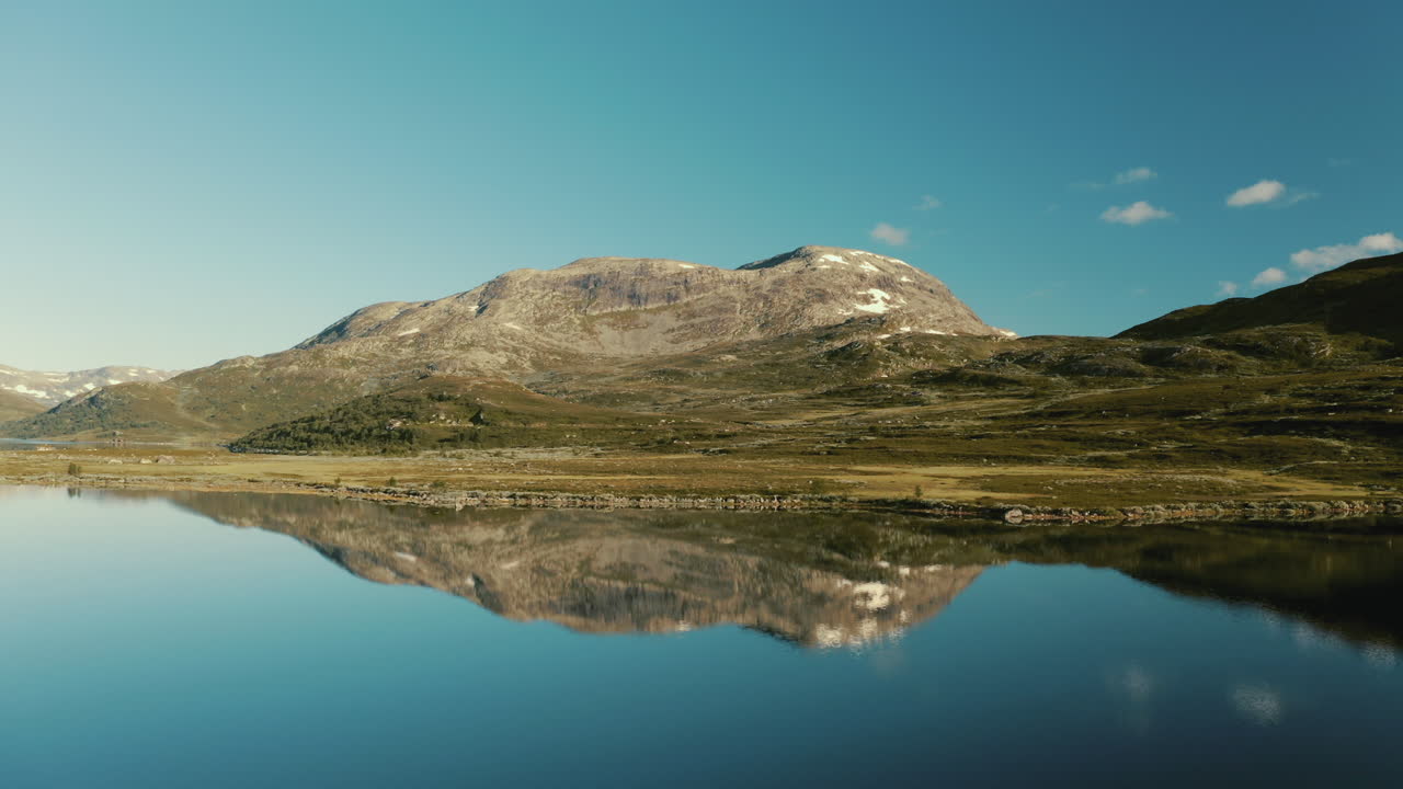drone volando hacia atrás revelando la suprema vista reflectante de la majestuosa montaña en el lago vavatnet en noruega - tiro de retroceso
