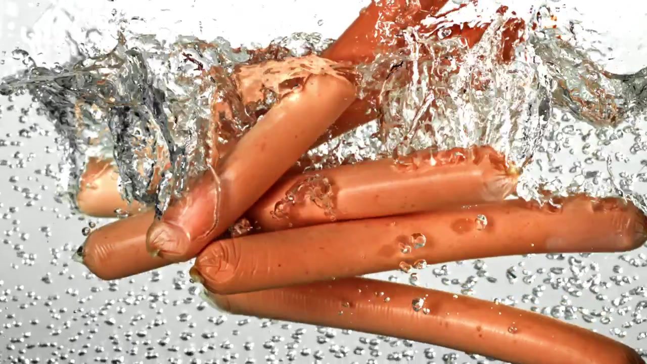 Salsicce che cadono nell'acqua bollente al rallentatore