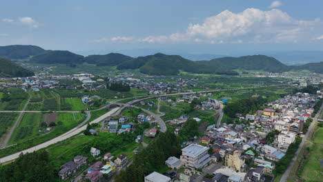 aerial view backwards over countryside homes and plantations, in nagano, japan