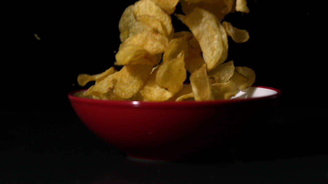 Chips falling into bowl on black surface