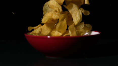 chips falling into bowl on black surface