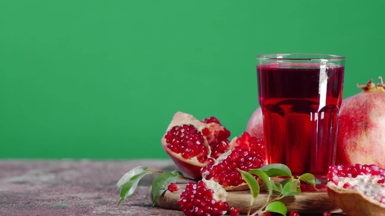 Granatæblejuice i glas på skærebræt roterer langsomt