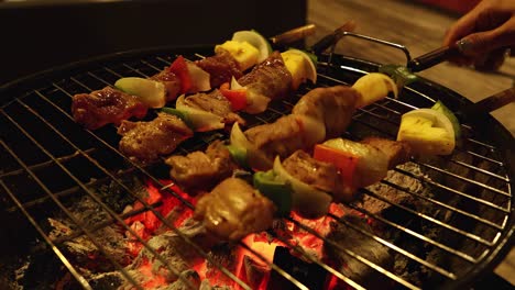a detailed view of skewers with meat and vegetables grilling over glowing charcoal on a metal grill.
