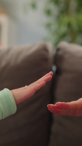 smiling little girl plays rock scissors paper with mother resting together on sofa closeup slow motion. having fun and spending time joyfully