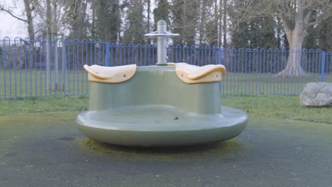 un parque infantil vacío con un carrusel giratorio en cámara lenta, en el centro de londres en un día frío y nublado