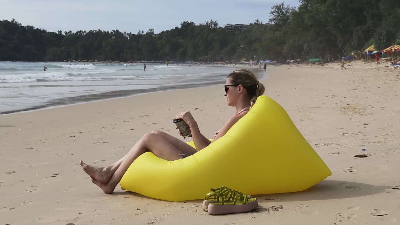 mujer relajándose en la playa en una silla inflable