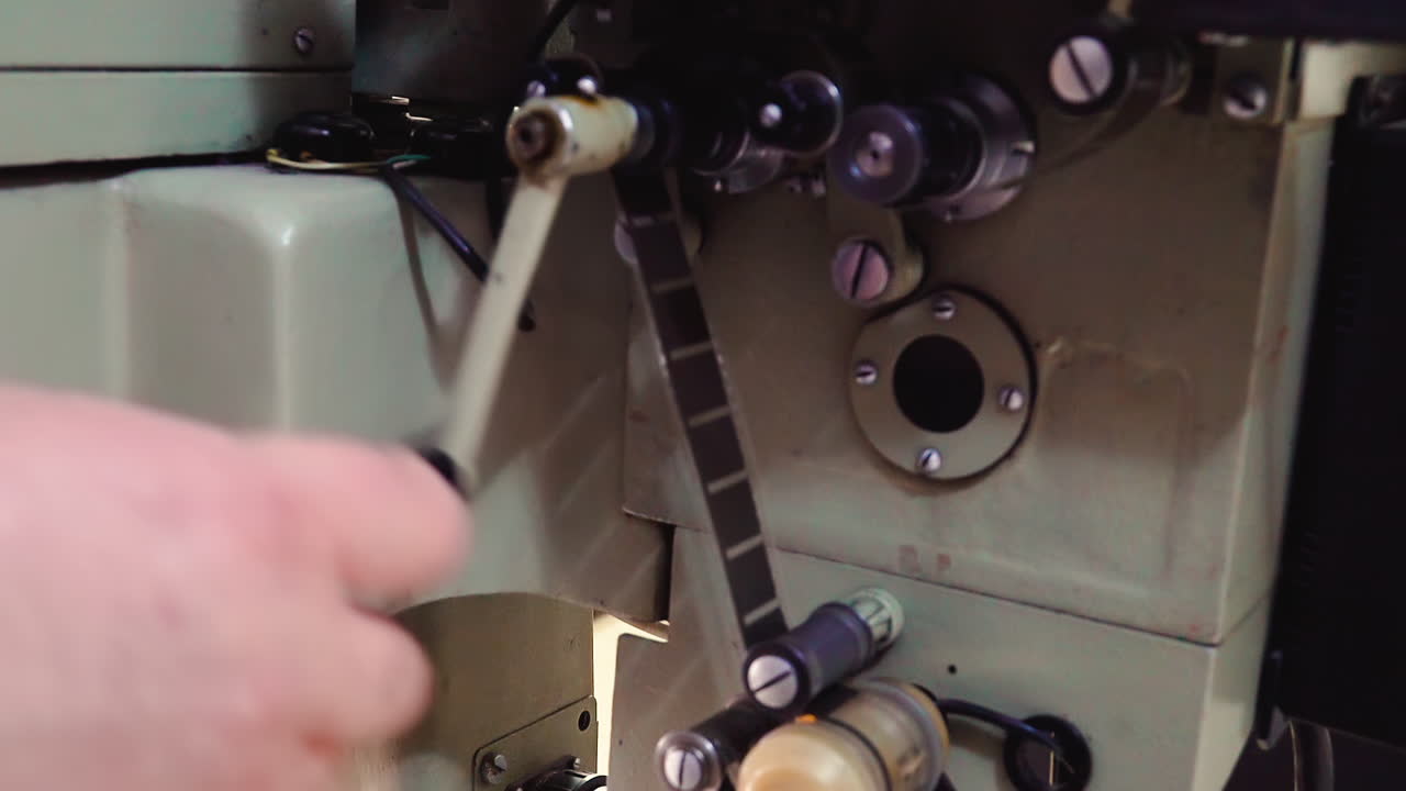 기술자 는 오래된 영화관 장비 의 손잡이 를 돌려 폴리 를 이동 시킨다