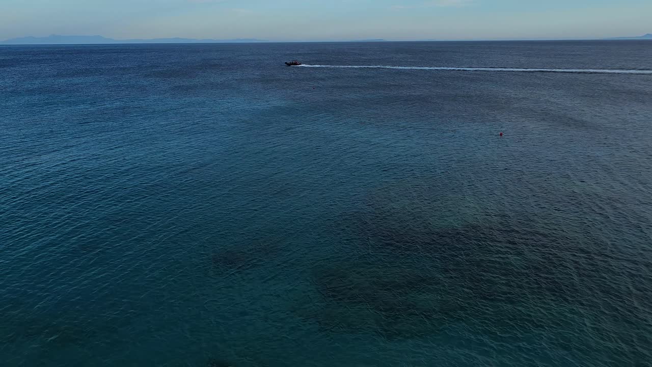 vasta superficie del mar y barco a motor navegando en el horizonte del mar azul profundo, en una hermosa bahía con playas y pueblos turísticos en albania, concepto de vacaciones de verano