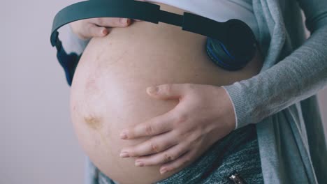 pregnant lady listens to music with baby dancing closeup