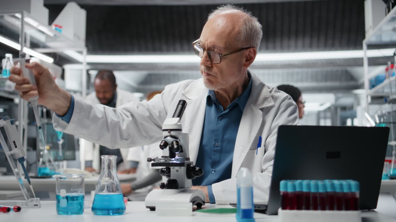 Elderly chemical engineer pipetting blue liquid into test tube