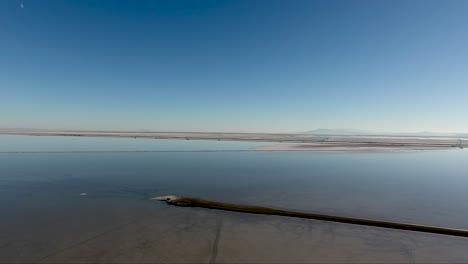 A-drone-shot-flying-over-the-Bonneville-Salt-Flats-shows-the-Salt-Flats-causeway-and-the-flooded-salt-pan