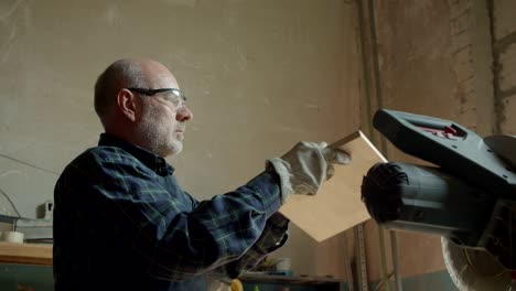 portrait of senior carpenter checks the quality sanding wooden board in manufacture.