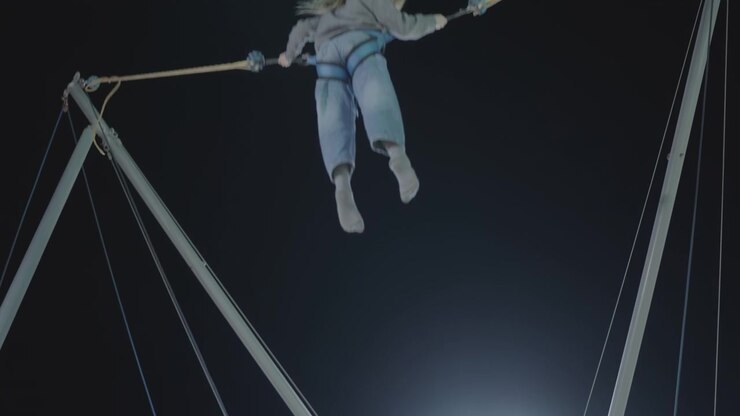 Young Woman Jumping on Bungee Trampoline at Night