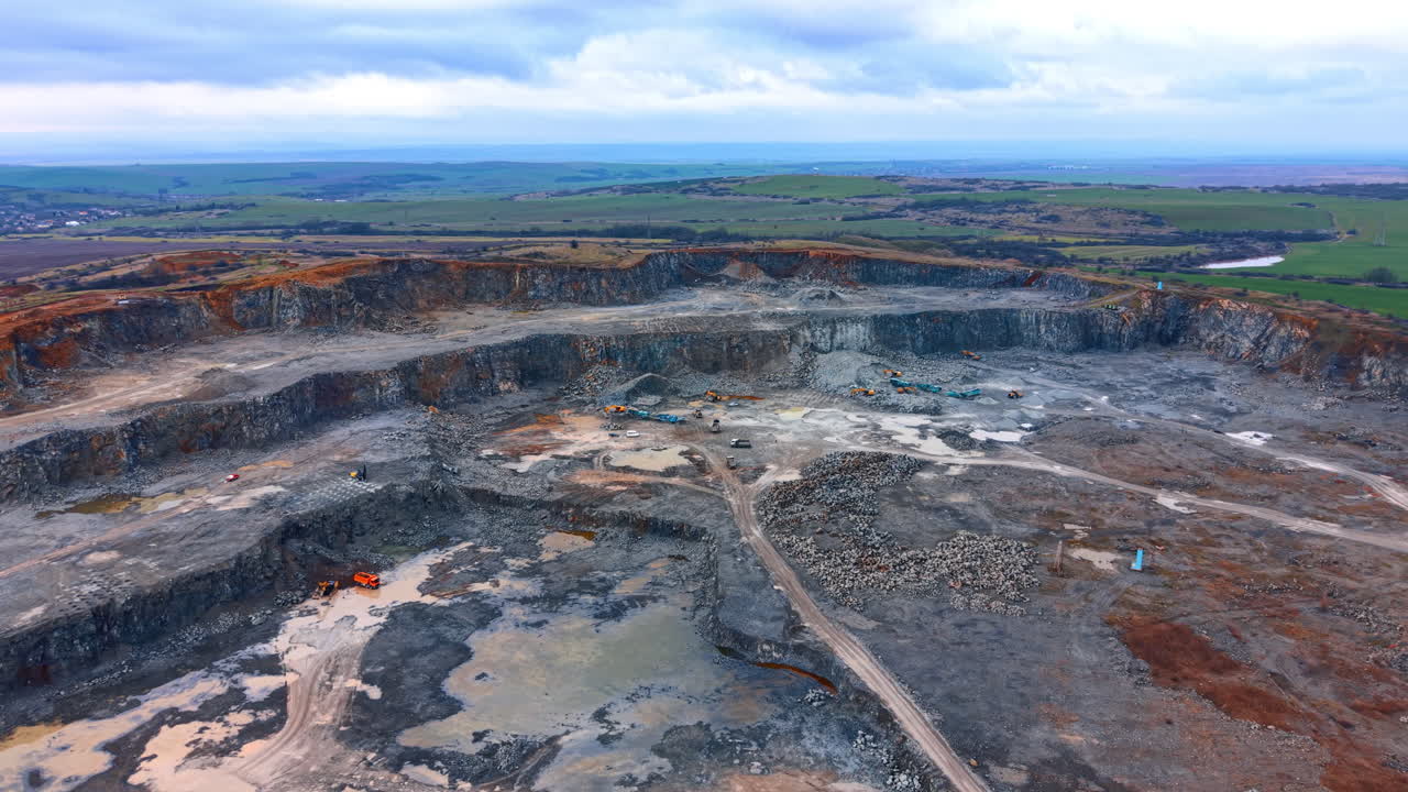 Quarry in rural landscape. A large quarry with machinery and workers, set in fields and hills on a cloudy countryside day