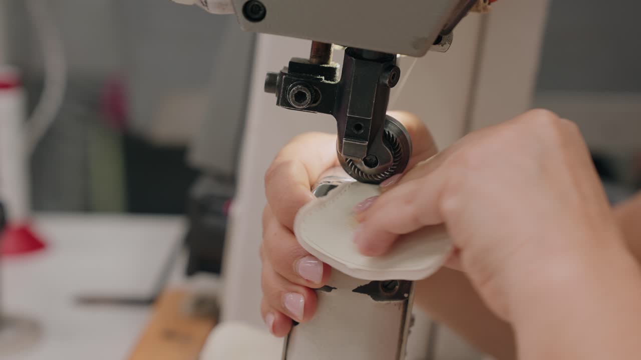 장인이 기계를 사용해 가죽 조각을 바느질하는 클로즈업 장면