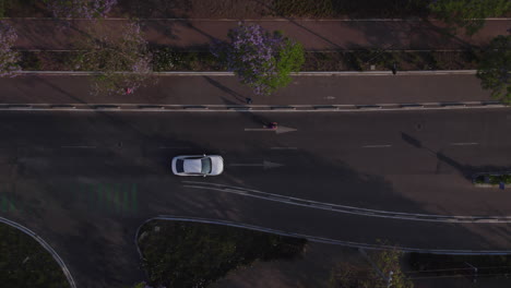 Luftverfolgung,-Draufsicht,-Weißes-Auto,-Das-Auf-Der-Straße-Fährt,-Fußgängerüberweg,-Hauptstraße-Passiert