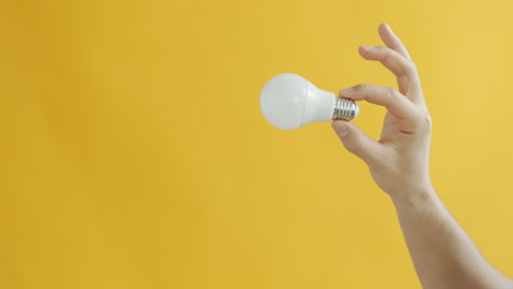 hand holding a light bulb on a yellow background