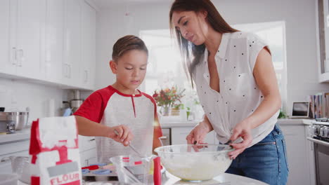 Pre-teen-Hispanic-boy-and-his-mum-making-cakes-in-the-kitchen-and-putting-them-in-the-oven,-close-up