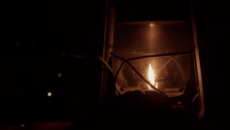 Dim-night-scene:-Hand-adjusts-flame-smaller-in-kerosene-oil-lantern