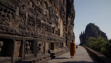 buddhist monk walking along ancient temple wall with carvings
