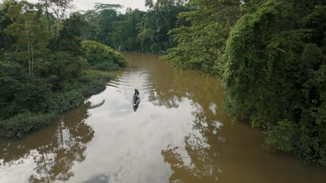 aerial view of small boat sailing on amazon river with lush vegetation in ecuador - drone shot