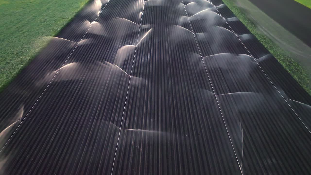 воздушный вид над сельскохозяйственной ирригационной системой, поливающим поле при заходе солнца - снимок с дрона