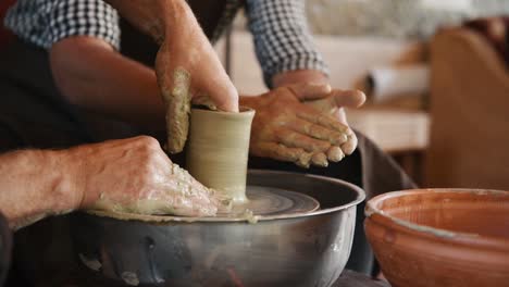 two guys use potter's wheel to create handmade clay product