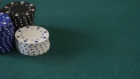 Close-up-of-a-poker-table-with-gambling-chips-as-a-hand-of-cards-is-dealt,-picked-up-and-the-player-places-a-bet