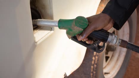 hand of african american man man filling up truck using fuel pump at petrol station