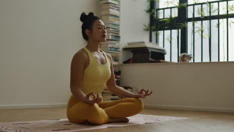 asiatic woman practicing meditation sitting crossleg in her home, doing mind yoga developing concentration, oriental spiritual practice