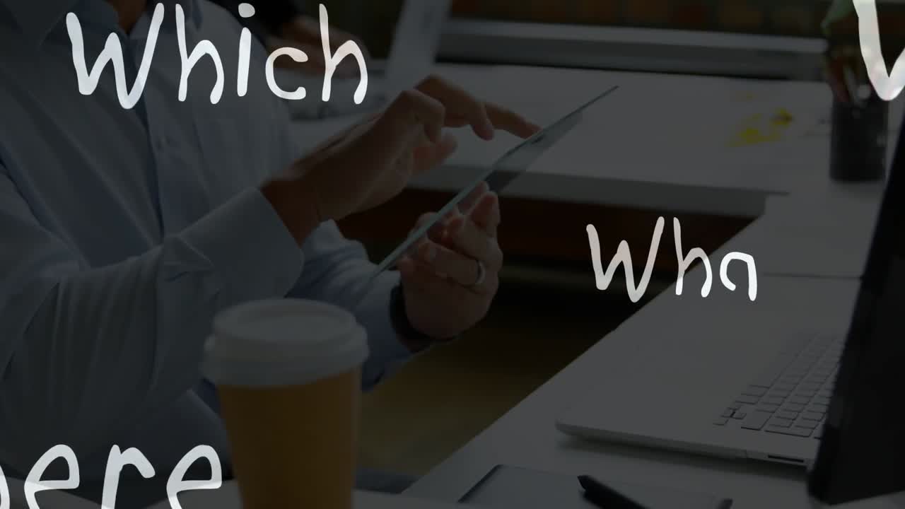 Man tapping tablet at shared desk, animating handwritten question words for business planning