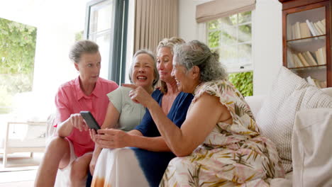 using a smartphone, a senior diverse group of women share a moment at home