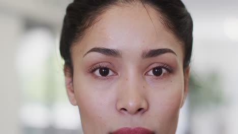 Video-close-up-portrait-of-eyes-of-biracial-female-medical-worker-looking-and-smiling-in-hospital