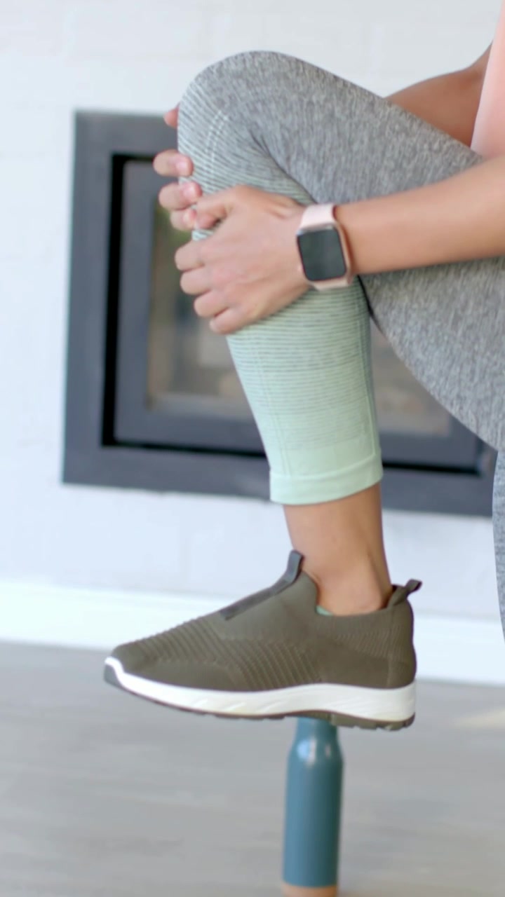 Video verticale: Una donna in leggings grigio-menta solleva il ginocchio destro, tenendolo su un supporto color verde acqua per bilanciarsi.