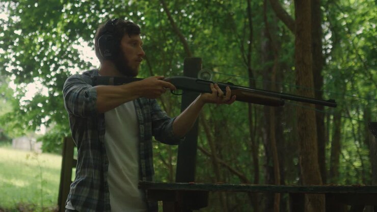 young American male embrace shotgun ready to shoot at the target in the forest, focus training exercise