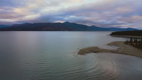 Lago-Kluane-Al-Atardecer-Dramático-Detrás-De-Las-Montañas,-Toma-Aérea-De-Drones