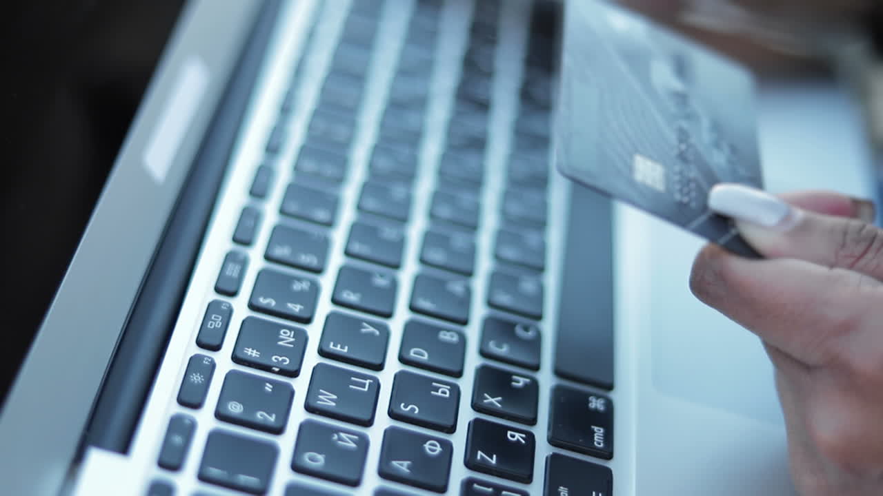Female hands typing card number on keyboard of laptop