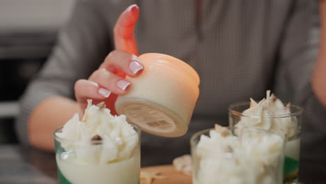 creative lifts glowing candle vessel placed among beautifully decorated desserts topped with white floral designs, creating warm elegant scene blending sweetness, creativity, and cozy atmosphere