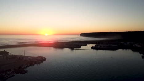 establishing shot of a fishing port with the sun setting on the horizon