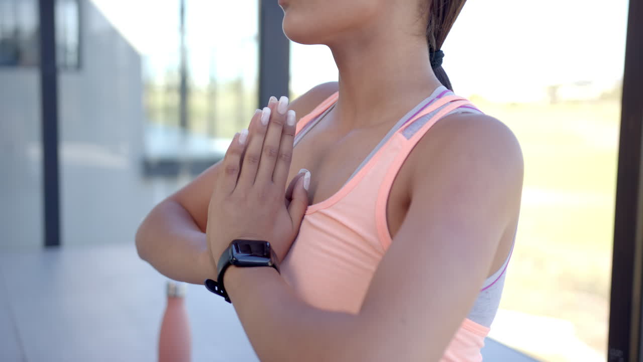 Practicing yoga, woman in sportswear meditating with smartwatch and water bottle
