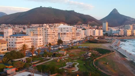 An-ascending-shot-in-a-seaside-park-revealing-the-suburb-of-Sea-Point-and-Lion's-Head