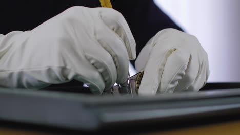 Professional-watch-collector-releasing-the-bracelet-of-a-luxury-watch-with-a-special-pin-tool,-wearing-white-gloves-and-performing-the-procedure-on-a-soft-mat