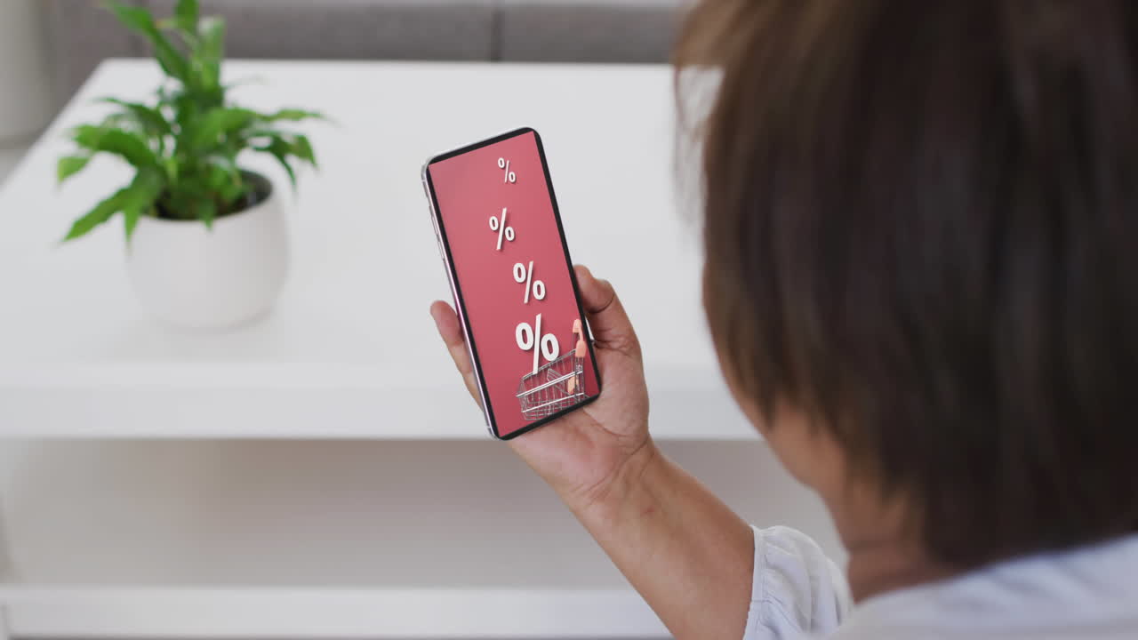 mujer biracial usando teléfono inteligente en casa compras en línea durante la venta, cámara lenta