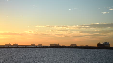 the harbor at long beach, california is crowded with cargo ships amidst a global supply chain crisis - sunset with ships in silhouette