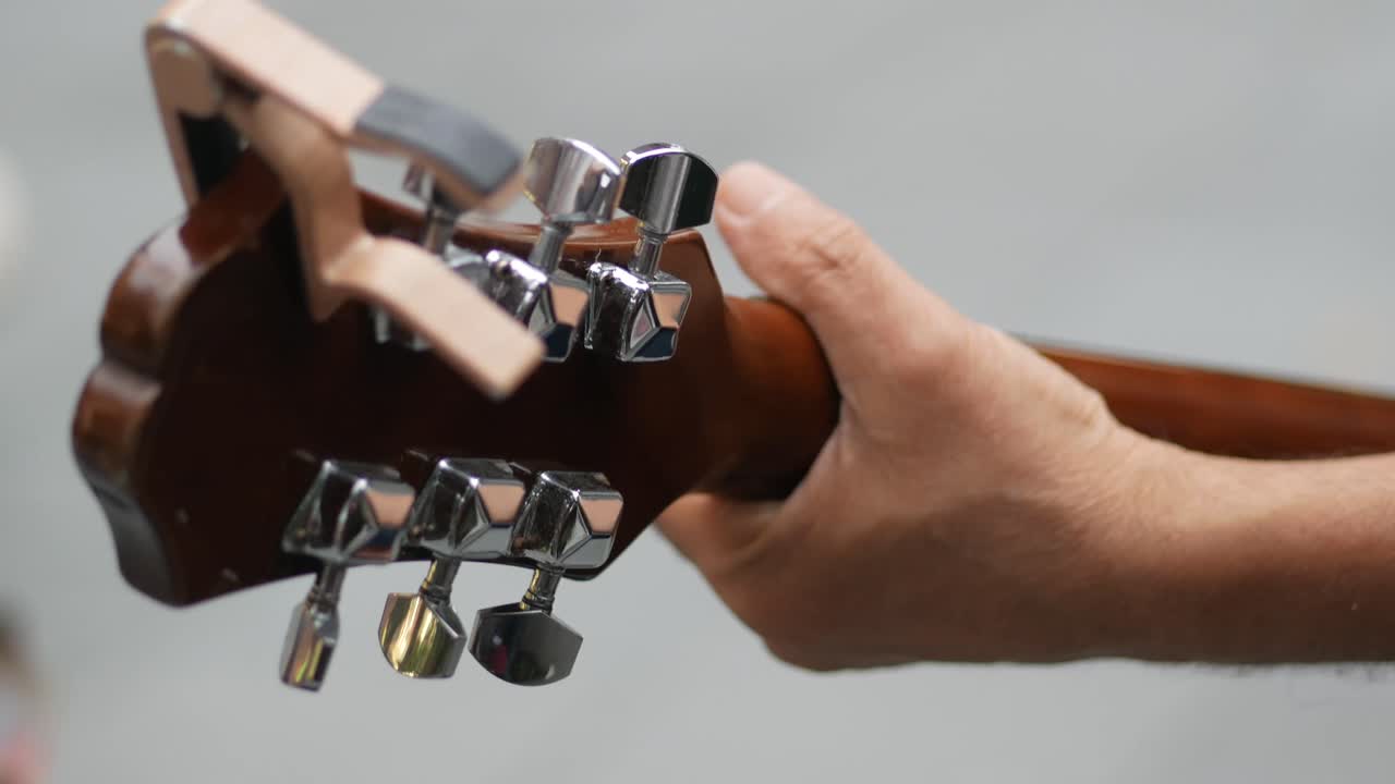 Close-up of a guitar headstock and hand