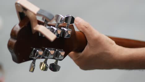close-up of a guitar headstock and hand