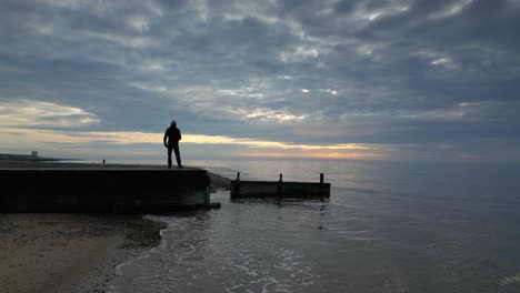 slow motion of man stood at jetty end enjoying sunset at fleetwood beach lancashire uk