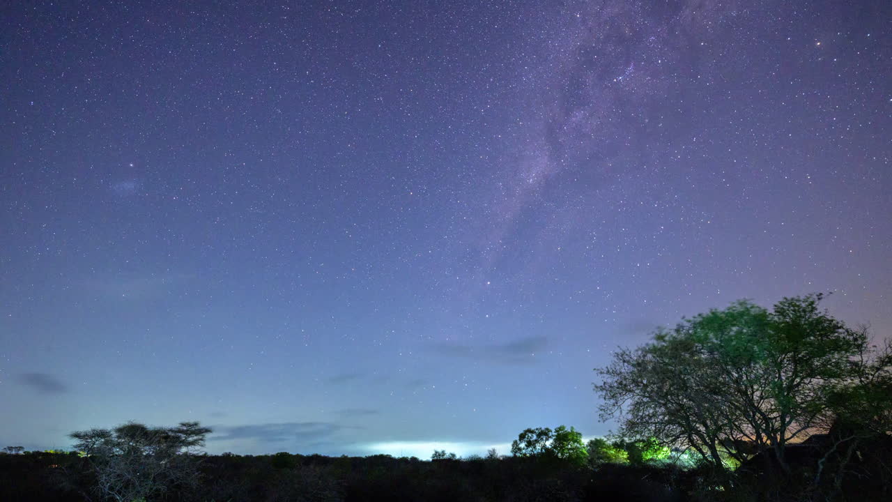 어떤 구름이 지나가고, 땅 앞에 있는 관목들과 함께 은하계의 시간 경과