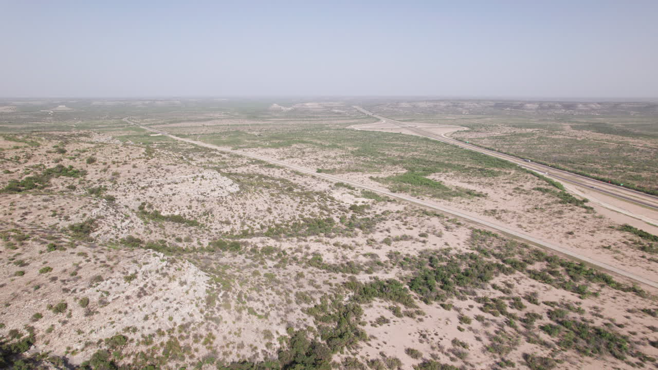 Aerial view of I-10 and a rural road in the west Texas desert with distant vehicles
